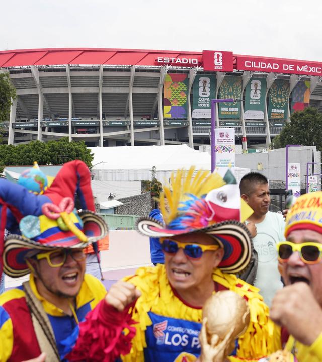 Vor dem Fußballstadion in Mexiko City stehen wie zum Karneval bunt gekleidete Männer mit Sonnebrillen und großen aufgeputzen Hüten.