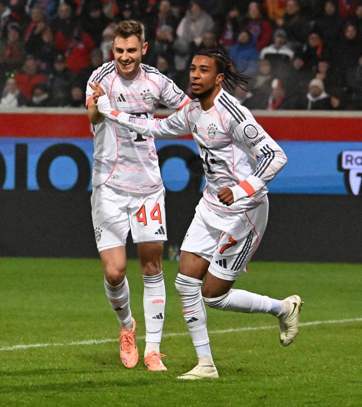 Bayerns Flügelspieler Michael Olise jubelt zusammen mit seinem Mitspieler Josip Stanisic nach seinem Treffer zum 0:2 gegen den 1.FC Heidenheim