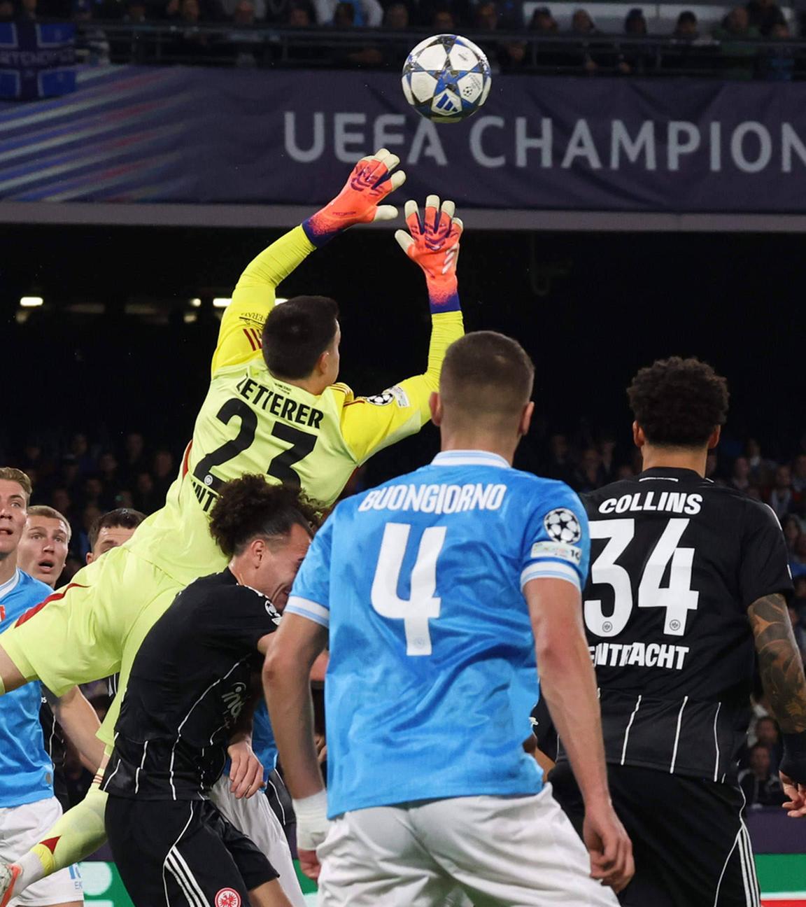 Michael Zetterer springt aus einer Gruppe Spieler heraus nach oben und blockt mit den Händen den heranfliegenden Ball ab.