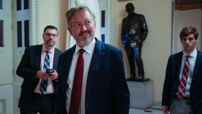 Thomas Massie im Innenraum eines Gebäudes. Massie blickt nach rechts aus dem Bild und grinst.