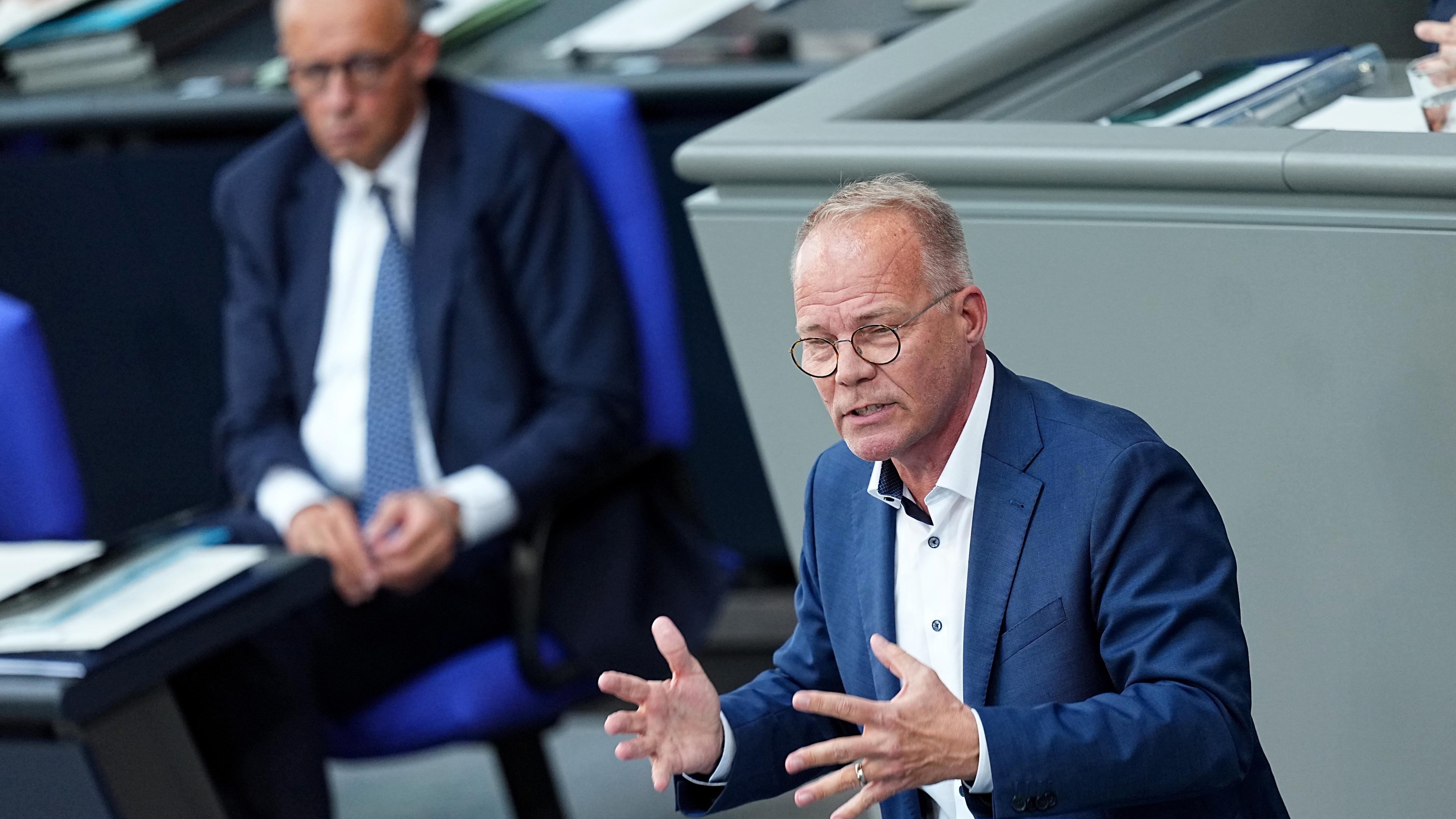 Matthias Miersch steht am Rednerpult im Bundestag. Im Hintergrund Bundeskanzler Merz mit eher ablehnendem Gesichtsausdruck.