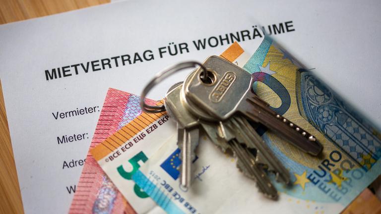 Berlin: Ein Mietvertrag für Wohnräume liegt zusammen mit Geldscheinen und Wohnungsschlüsseln auf einem Tisch