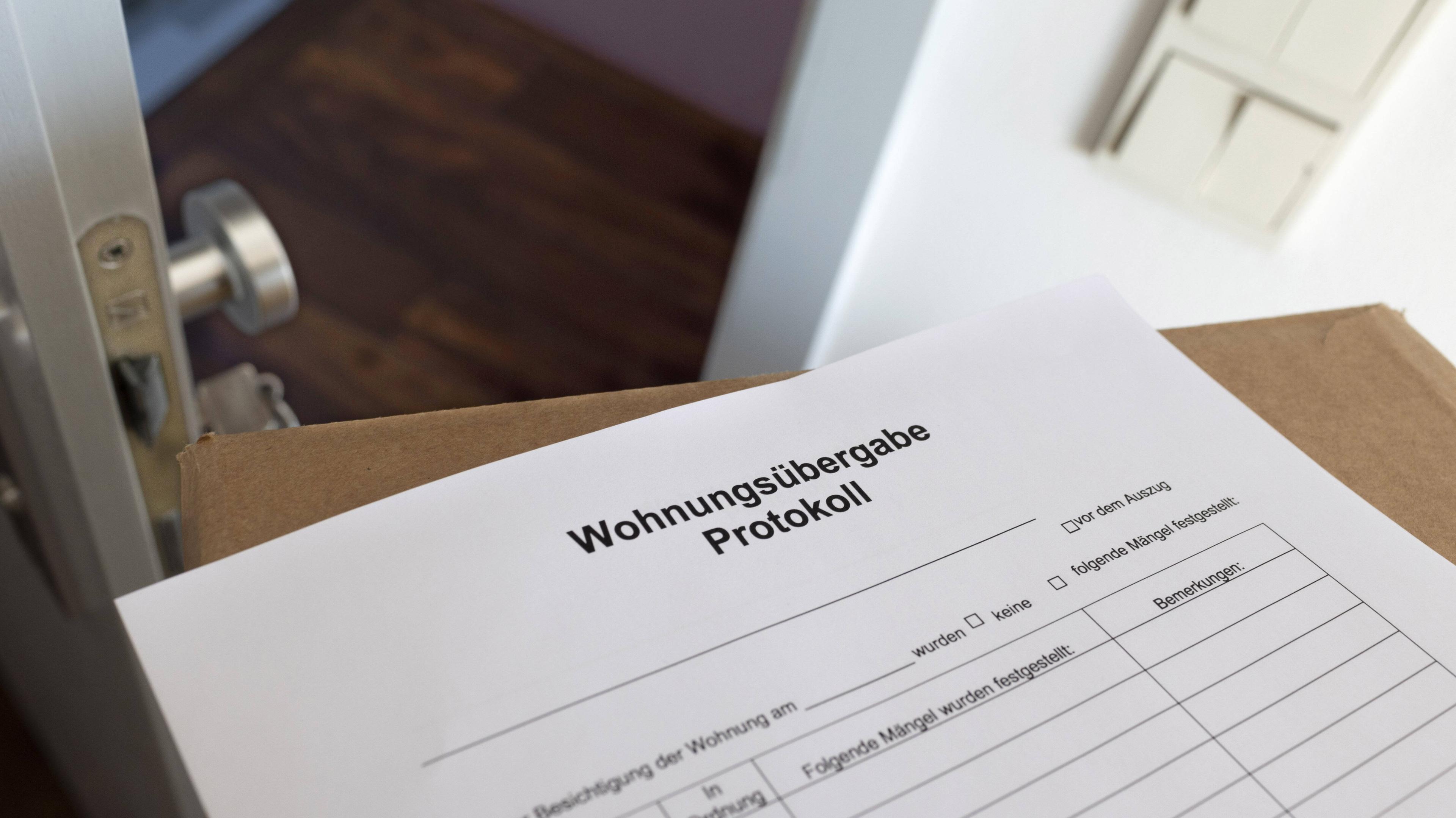 Ein Übergabeprotokoll liegt auf einem Umzugskarton in einer leeren Wohnung.
