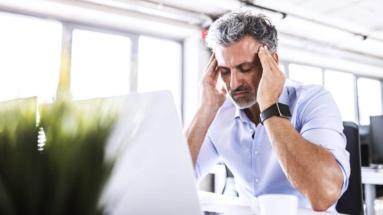 Mann hat Migräne-Attacke am Arbeitsplatz
