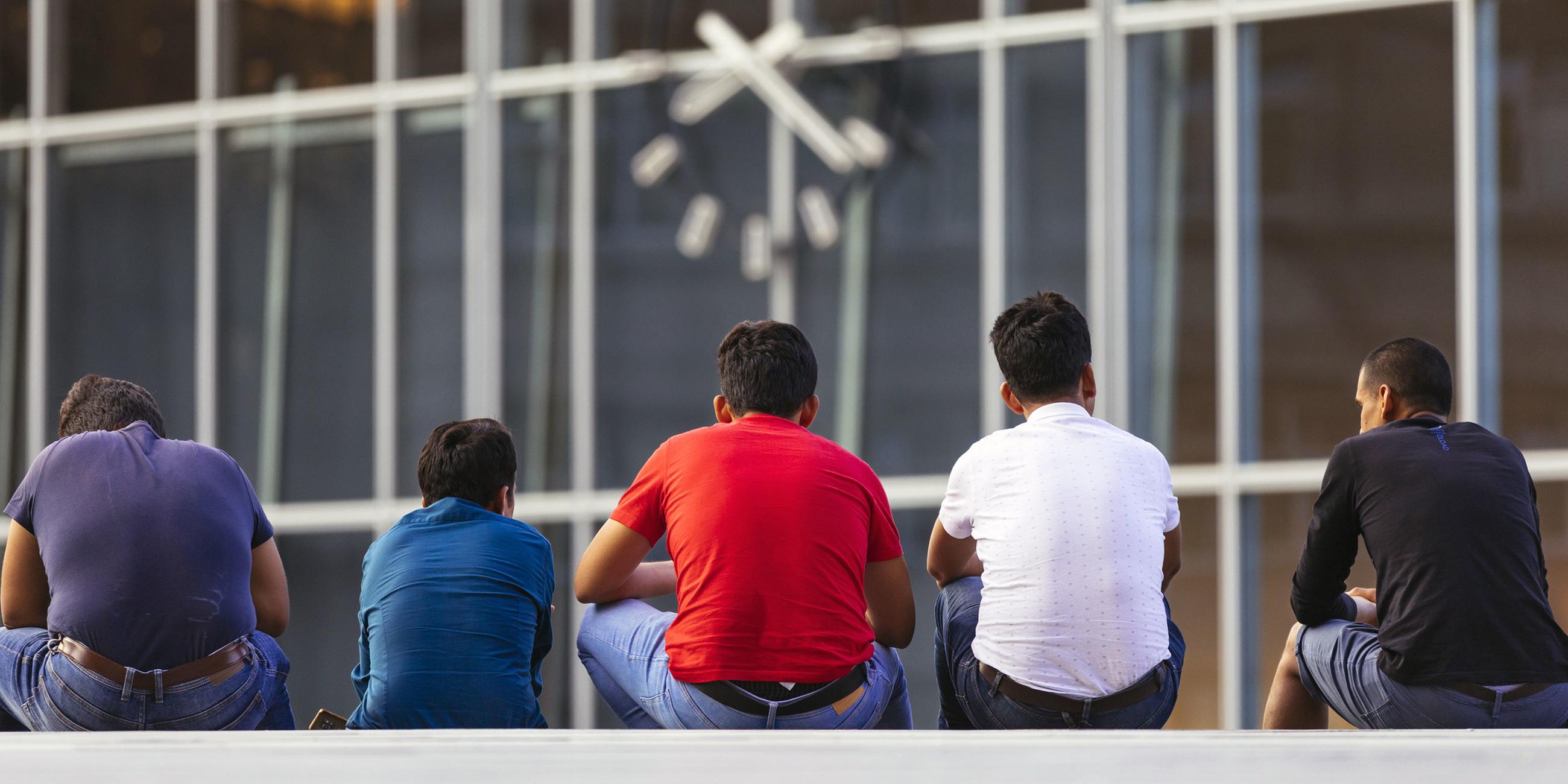 Migranten sitzen auf der Bahnhofstreppe am Kölner Hauptbahnhof (24.07.2018)