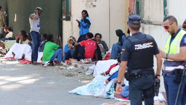 Polizisten stehen in Ceuta neben jungen Migranten, die einige Tage zuvor in Ceuta angekommen waren.