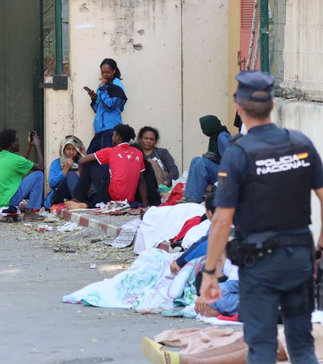 Polizisten stehen in Ceuta neben jungen Migranten, die einige Tage zuvor in Ceuta angekommen waren.