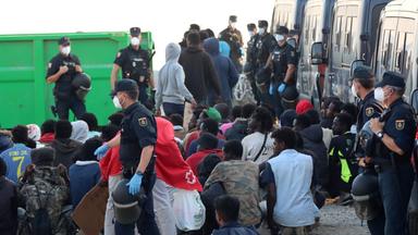 Polizeibeamte eskortieren Migranten vom Strand Trampolin zu einer Unterkunft in Ceuta, Spanien, am 20. August 2026.