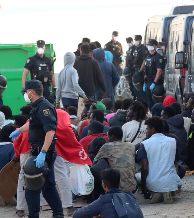 Polizeibeamte eskortieren Migranten vom Strand Trampolin zu einer Unterkunft in Ceuta, Spanien, am 20. August 2026.