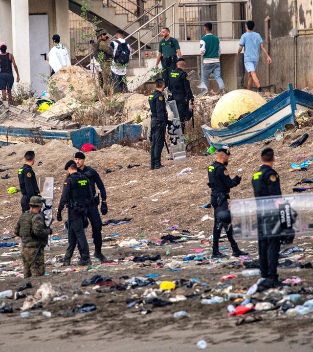 Spanien, Ceuta: Soldaten der spanischen Armee und Beamte der Guardia Civil stehen Wache, während Migranten aus der spanischen Exklave Ceuta nach Marokko zurückkehren.