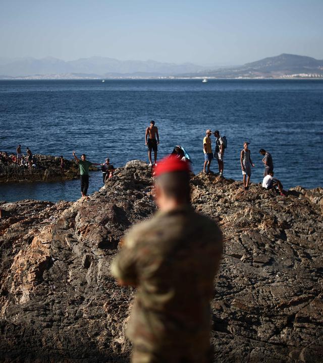 Angehörige der Infanterieeinheit „Regulares“ der spanischen Armee beobachten am 02.08.2026 eine Gruppe von Migranten in der Nähe des Grenzposten der spanischen Exklave Ceuta.