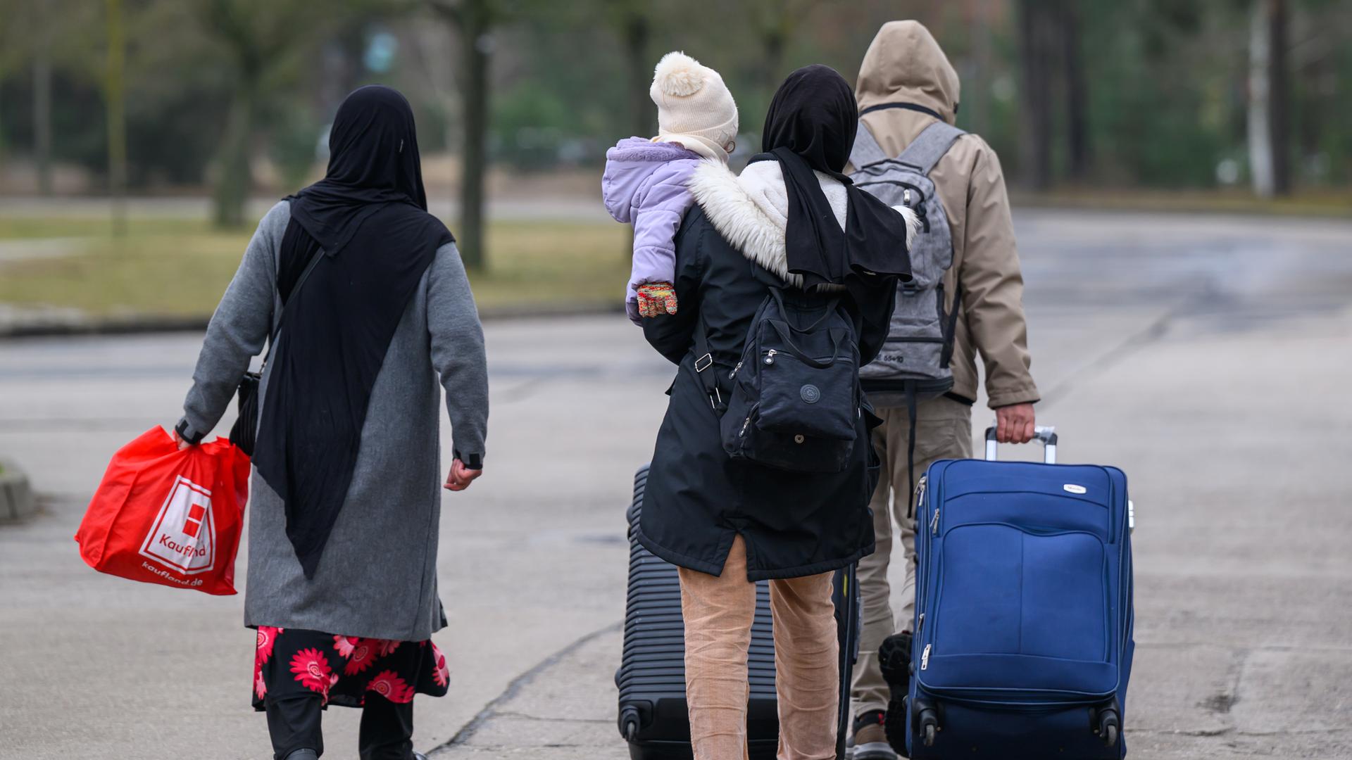 Migranten verlassen mit Reisegepäck das Gelände der Zentralen Ausländerbehörde Brandenburgs (ZABH).