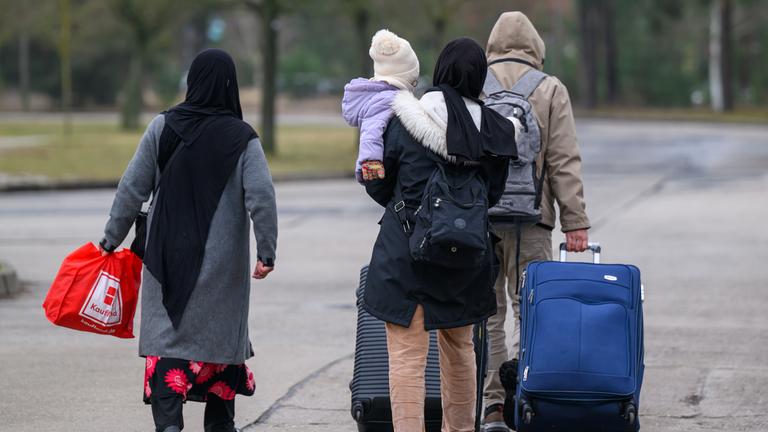 Migranten verlassen mit Reisegepäck das Gelände der Zentralen Ausländerbehörde Brandenburgs (ZABH).