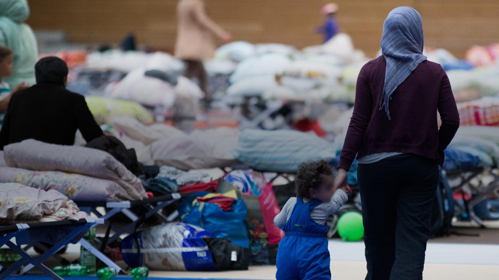 Eine Frau läuft mit einem Kind an der Hand durch eine Flüchtlingsunterkunft