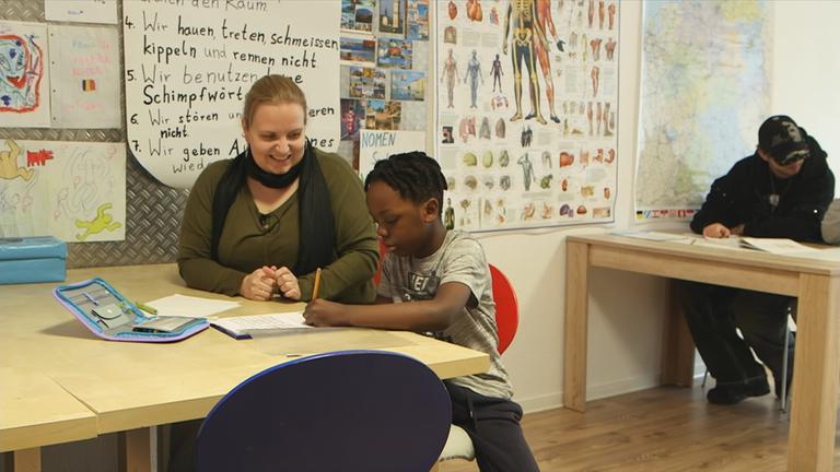 Frau hilft Jungen bei Hausaufgaben 