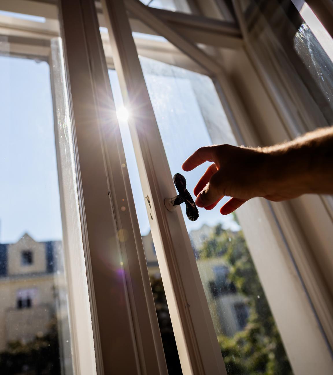 Eine Person öffnet in einer Berliner Wohnung ein Fenster, wobei die Sonne hereinscheint. Forscher haben berechnet, wie viele winzige Plastikteilchen sich beim Atmen in unseren Körpern ansammeln könnten.