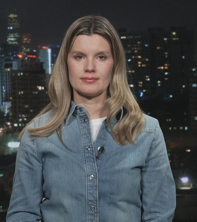 ZDF-Korrespondentin Elisabeth Schmidt vor einer Grafik von Peking bei Nacht