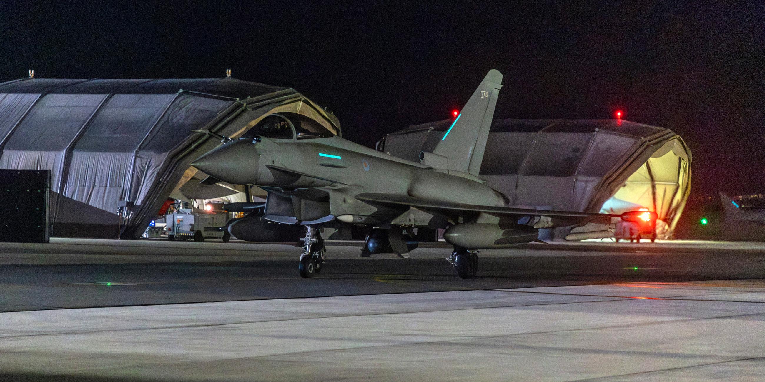 Ein Militärflugzeug auf einem Rollfeld in tiefer Nacht.
