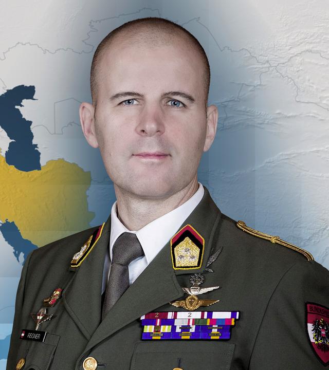 Oberst Marus Reisner. Im Hintergrund ist eine Karte, in der die Ukraine und Iran gelb markiert sind. 