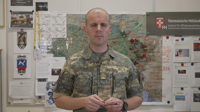 Oberst Markus Reisner vor einer Karte der Ukraine bei der die Front eingezeichnet ist