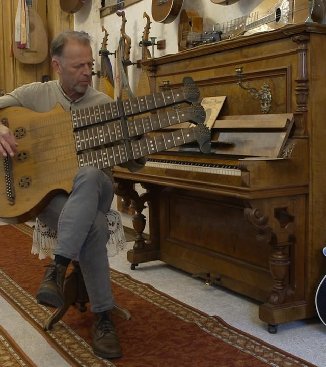 Ein Mann mit einer besonderen historischen Gitarre in der Hand