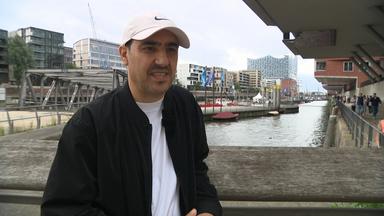 Homayoon Pardis steht auf einer Brücke in Hamburg und spricht.