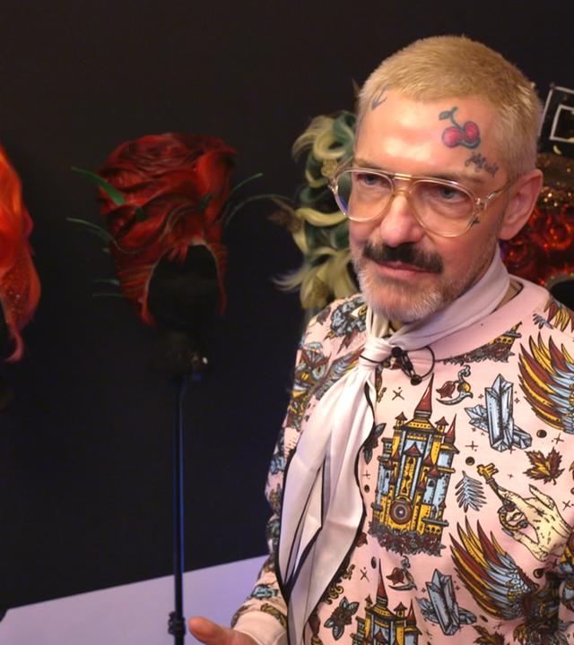 Mima-Mensch Karl Gadzali vor seinen extravaganten, bunten Perücken 