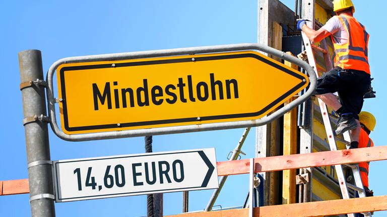 Ansteigender Wegweiser mit Aufschrift Mindestlohn vor Baustelle