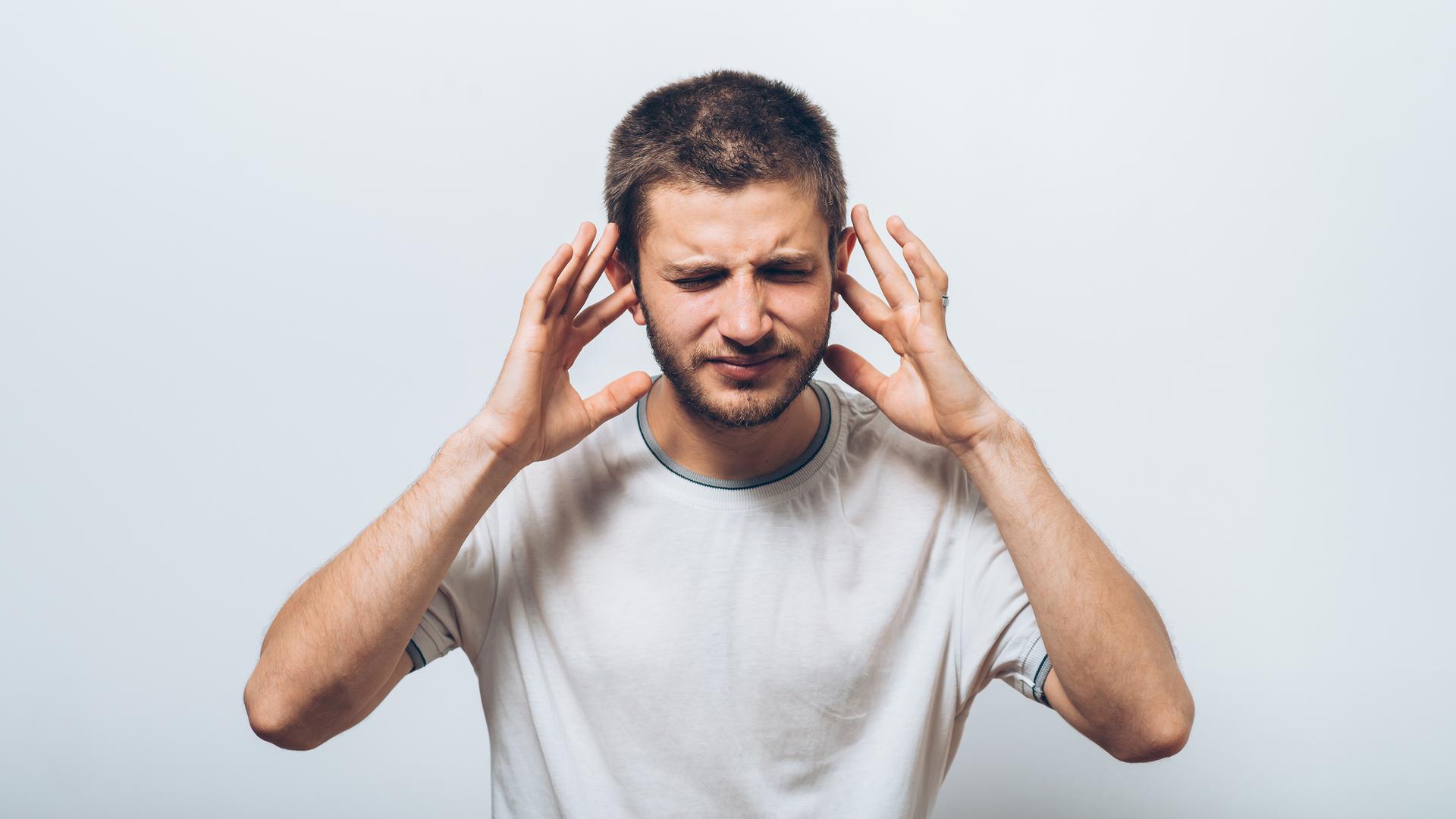 Mann hält sich die Ohren zu.