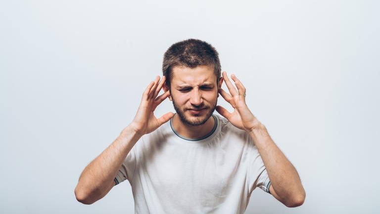 Mann hält sich die Ohren zu.