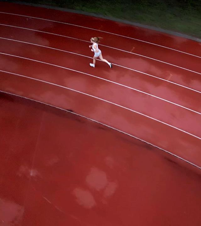 Junge Frau läuft Runden auf einer 400-Meter-Bahn