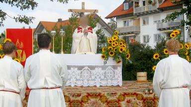 Screenshot aus Video: Eine Andacht im Freien, ein Pfarrer in der Bildmitte (Gesicht verpixelt), Messdiener im Vordergrund