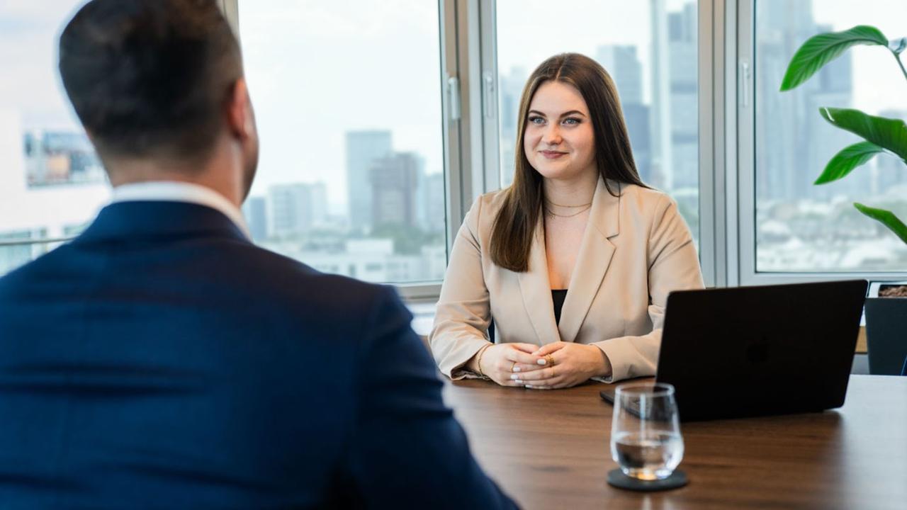 Eine Frau und ein Mann sitzen sich an einem Schreibtisch gegenüber
