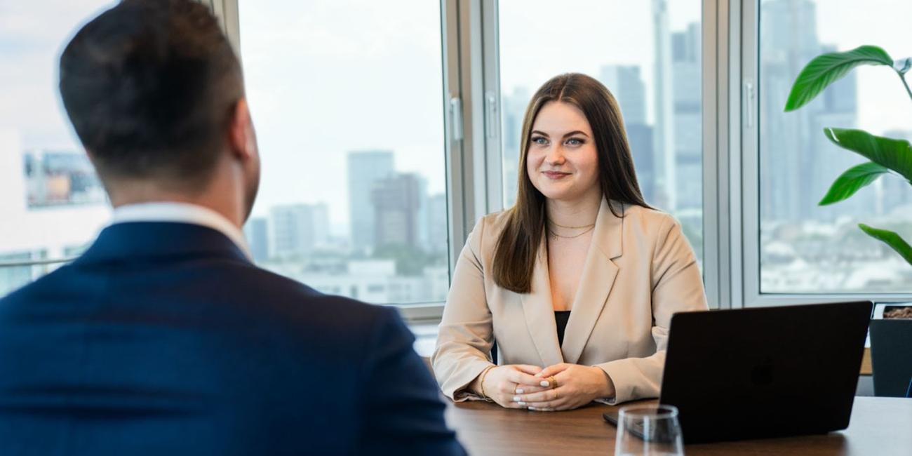 Eine Frau und ein Mann sitzen sich an einem Schreibtisch gegenüber