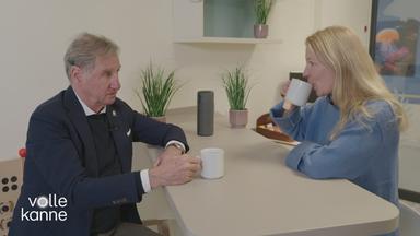 Mann mit Hörgerät und Frau sitzen an Küchentsich