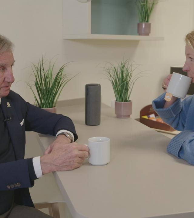 Mann mit Hörgerät und Frau sitzen an Küchentsich