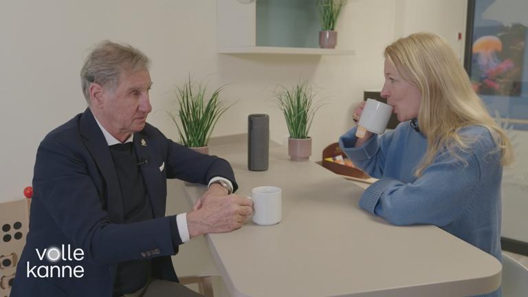 Mann mit Hörgerät und Frau sitzen an Küchentsich