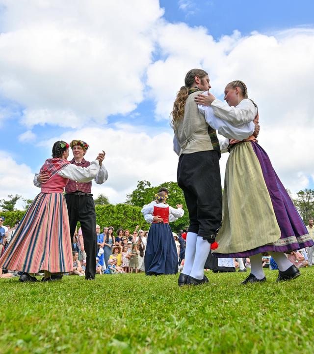 Teilnehmer der Mittsommerfeierlichkeiten in traditioneller Kleidung tanzen in Göteborg um den Mittsommerbaum.