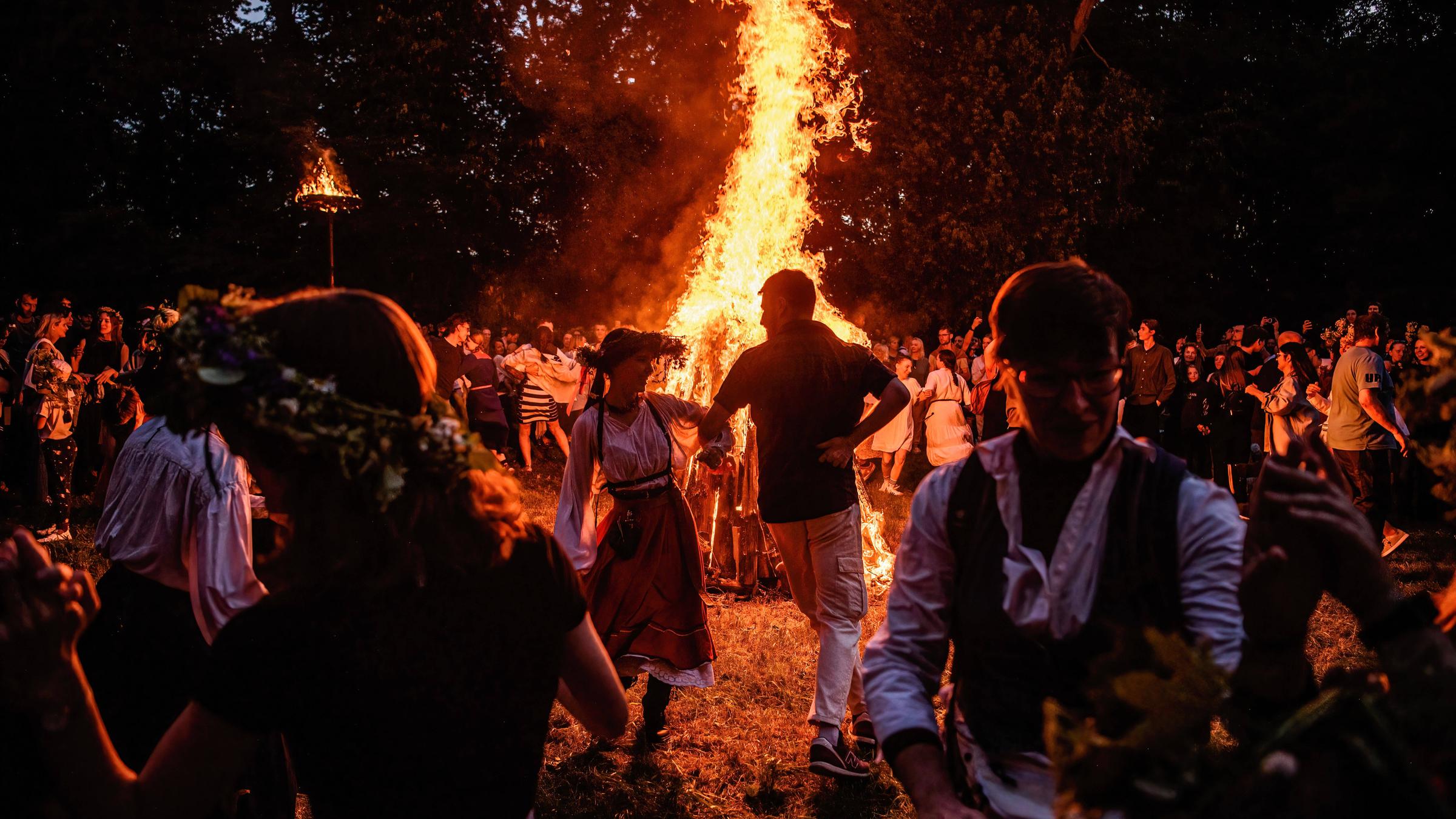 Menschen tanzen um ein Lagerfeuer, während sie den Johannistag und die Sommersonnenwende am 06.06.2025 in Vilnius feiern. 