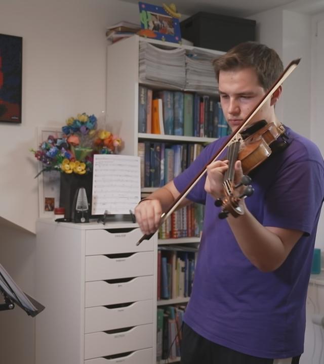 Ein Jugendlicher spielt in seinem Zimmer Geige