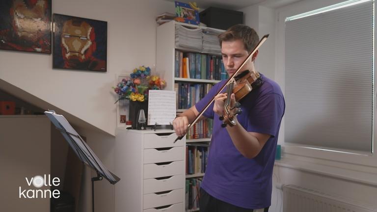 Ein Jugendlicher spielt in seinem Zimmer Geige