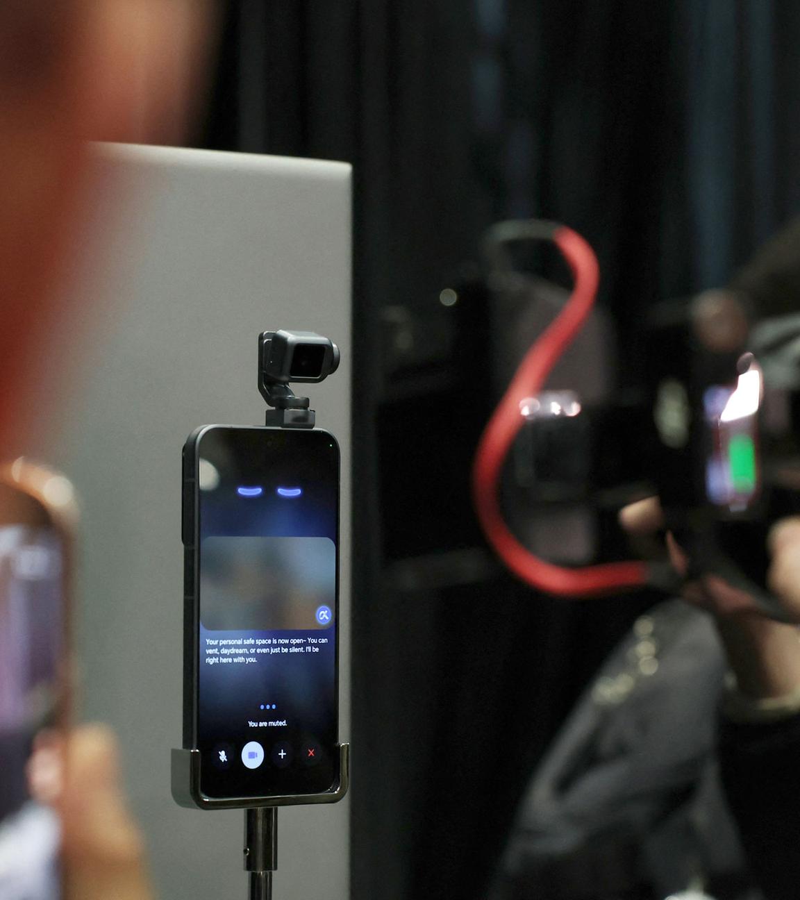 Eine verschwommene Kamera im Vordergrund wird auf ein fokussiertes Handy gehalten, das auf dem Mobile World Congress ausgestellt ist.