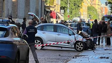 Polizisten stehen am stark beschädigten Tatfahrzeug in einem abgesperrten Bereich.