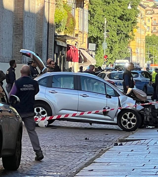 Polizisten stehen am stark beschädigten Tatfahrzeug in einem abgesperrten Bereich.
