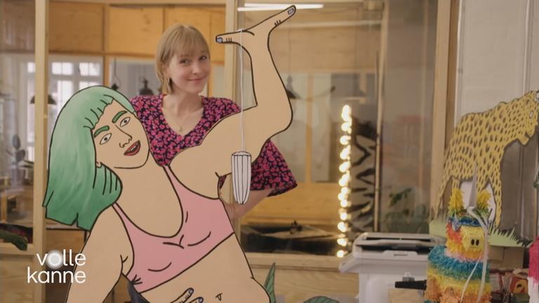 Frau im Büro, vor ihr steht eine Pappfigur die ein Tampon hochhält