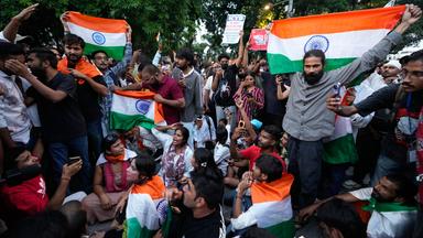 Eine Gruppe von Demonstranten in Neu-Delhi schwenkt indische Fahnen.