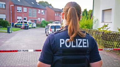 Eine Polizistin steht am Tatort vor einem Absperrband in Moers (Nordrhein-Westfalen)