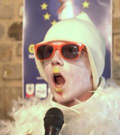 Ein Junge der eine weiße Mütze, eine rote Sonnenbrille und weiße Schminke trägt, um sich als Möwe zu verkleiden. Sein Mund ist geöffnet, während er die Möwenlaute macht.