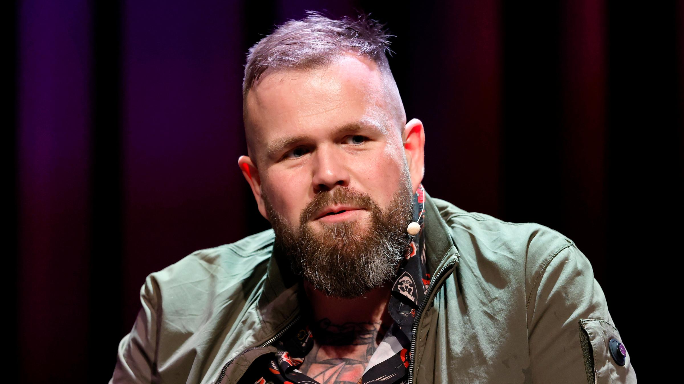 Sänger Jan Gorkow (Monchi) von der Band Feine Sahne Fischfilet sitzt auf einer Bühne.