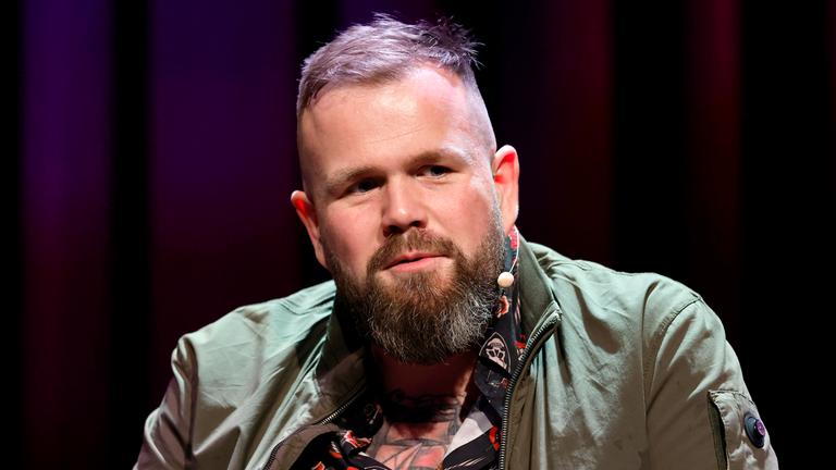 Sänger Jan Gorkow (Monchi) von der Band Feine Sahne Fischfilet sitzt auf einer Bühne.